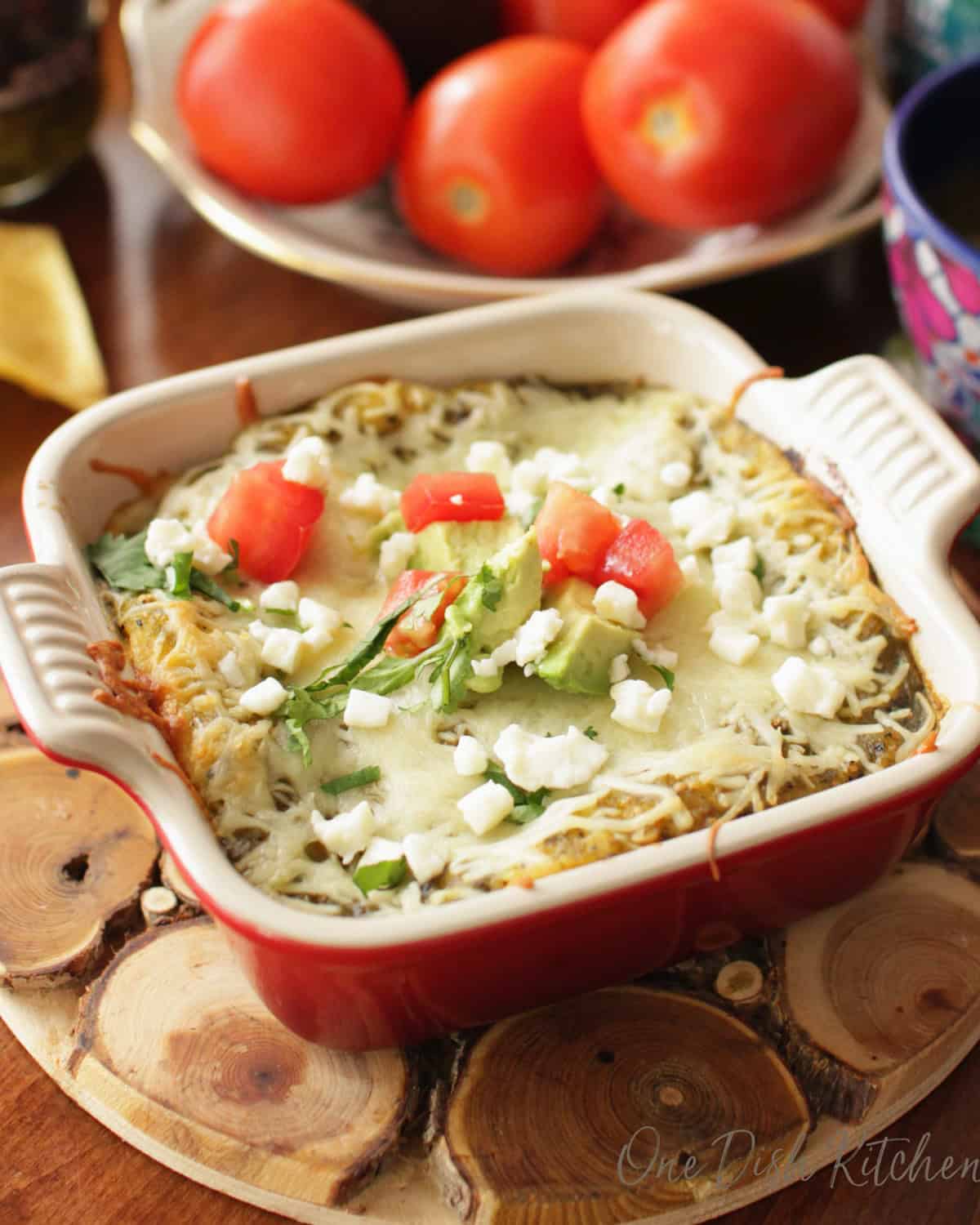 single serving enchiladas verde in a red dish.