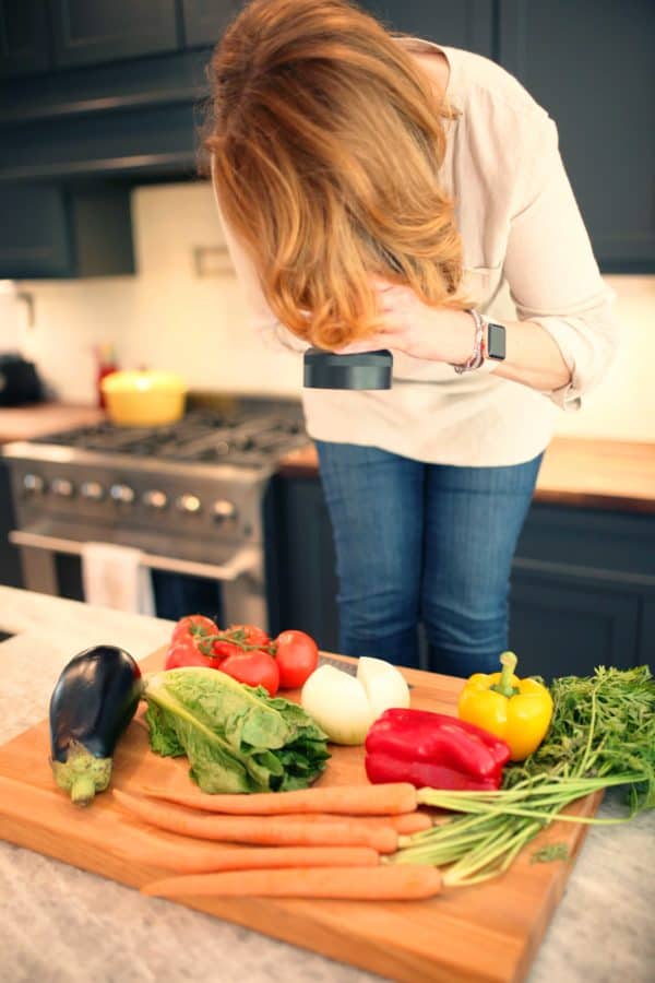 Joanie Zisk photographing a tray of fresh vegetables.