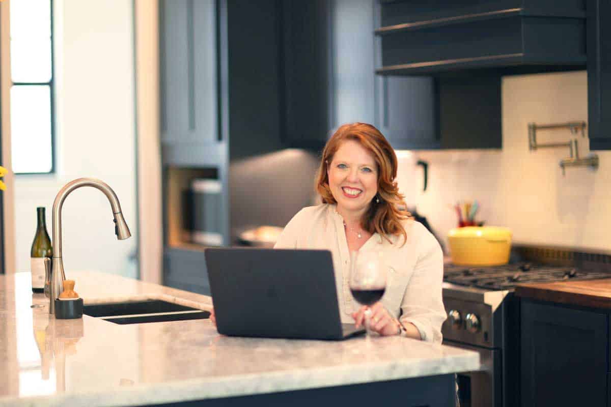 Joanie Zisk sitting at a kitchen counter on the computer.