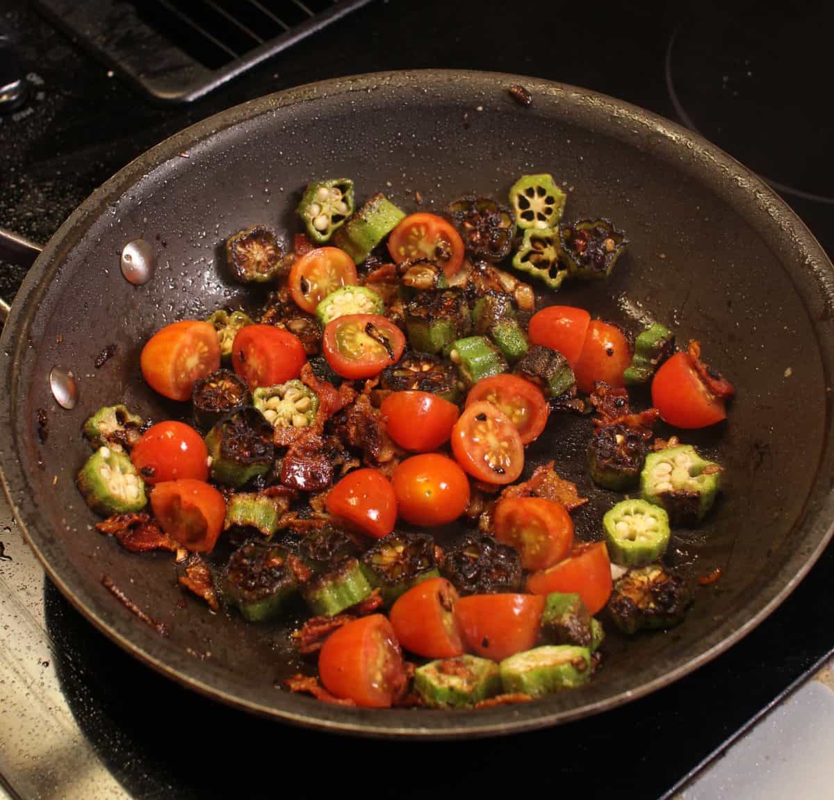 a frying pan filled with sliced okra and tomatoes.