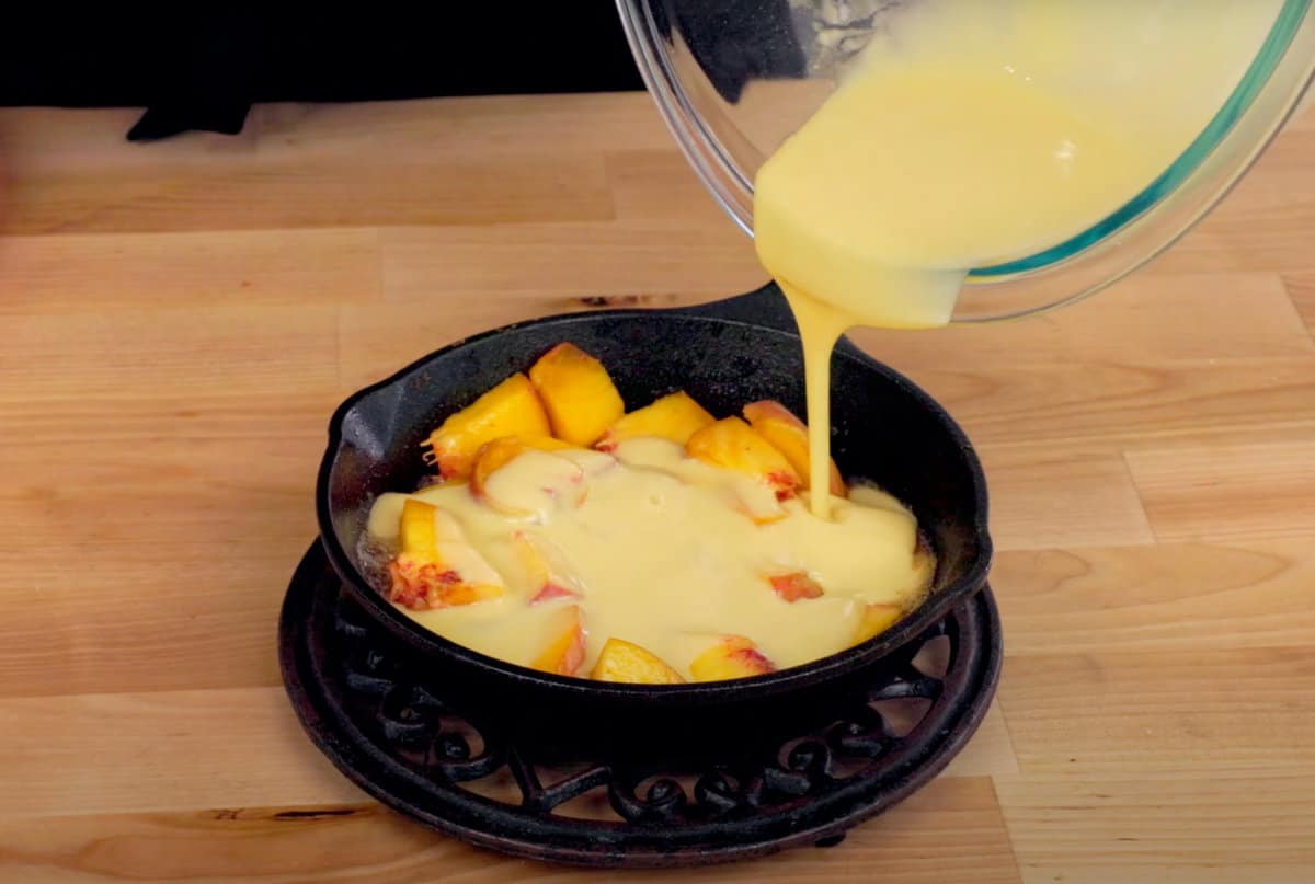 pouring batter over fresh chopped peaches in a skillet