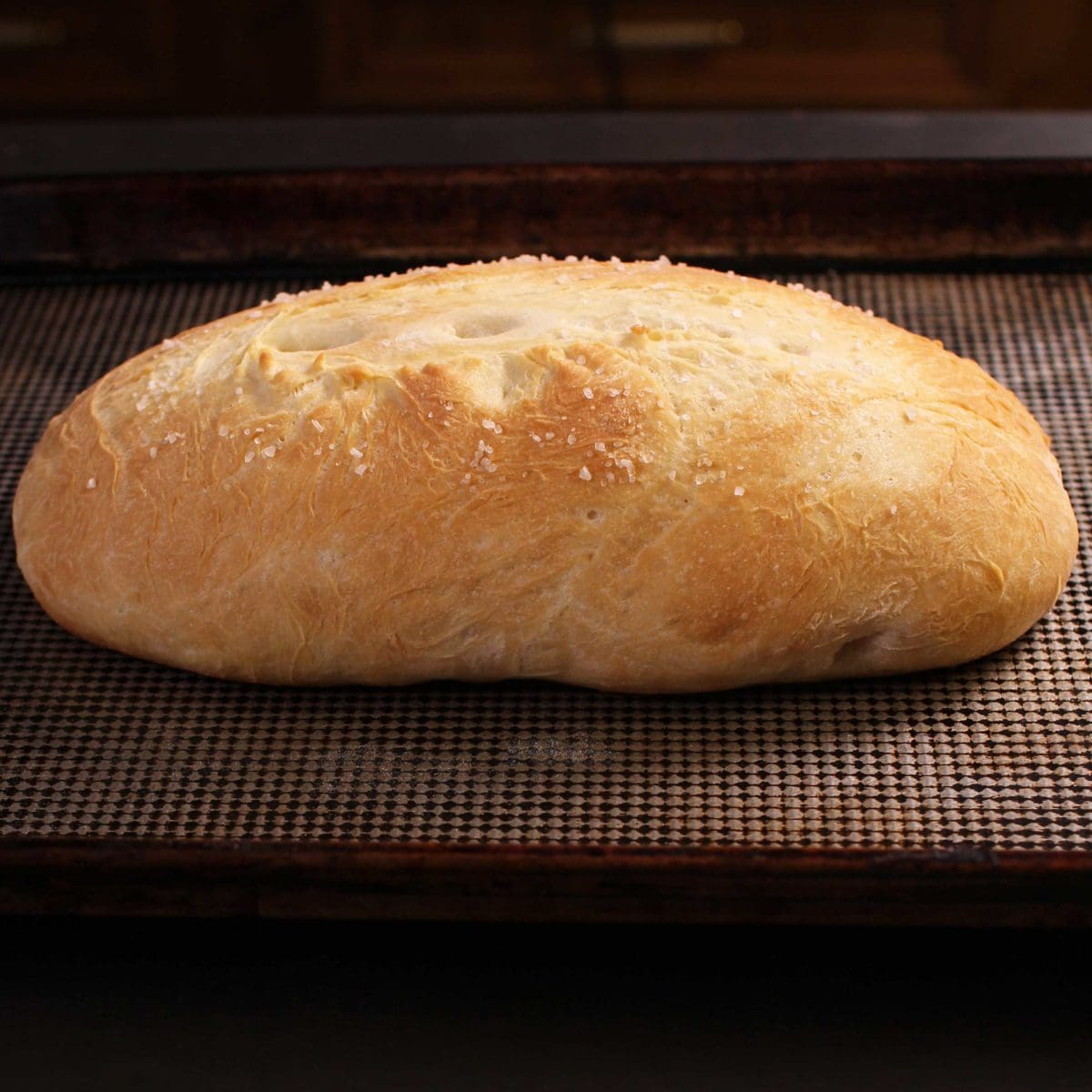 A loaf of baked french bread on a baking sheet.