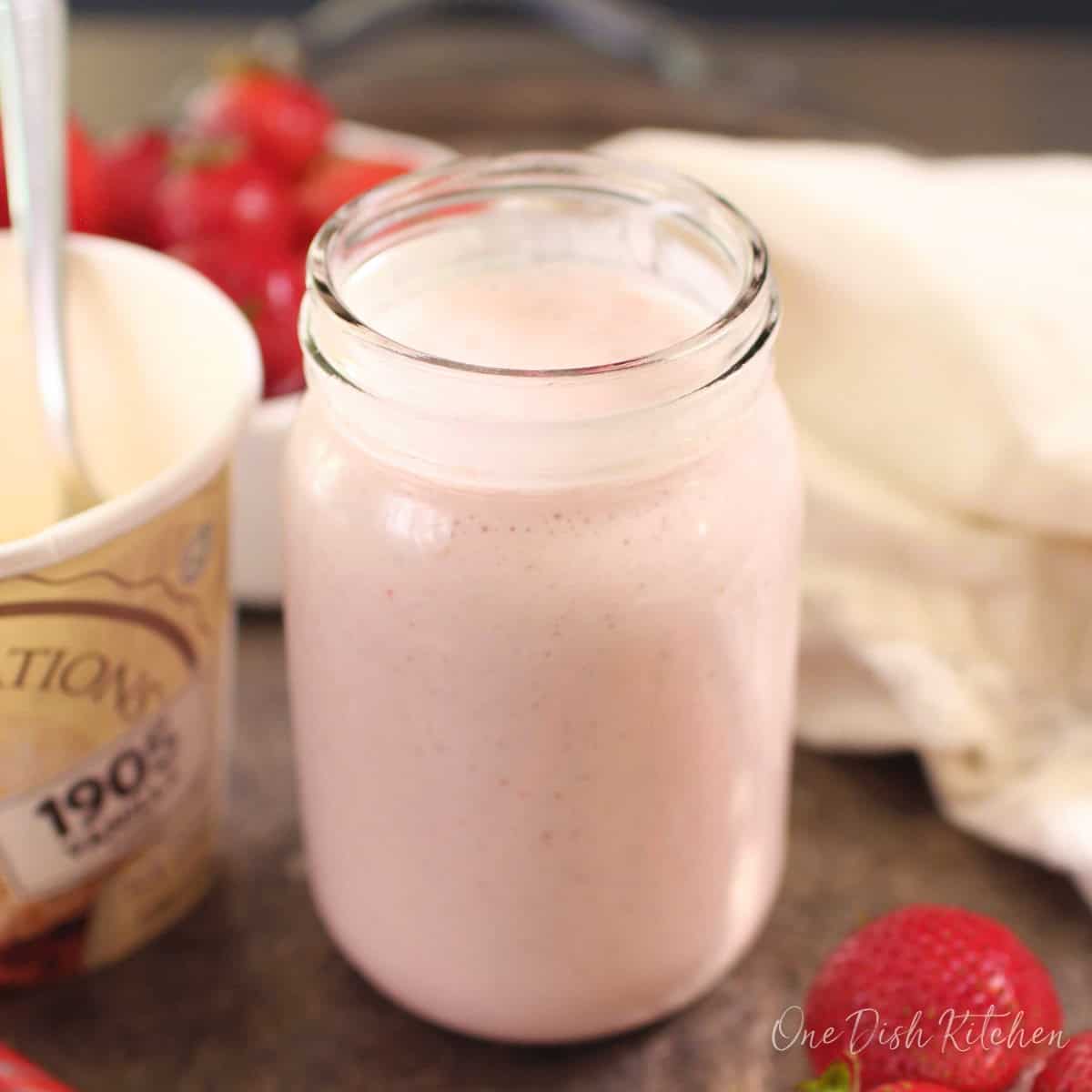a homemade strawberry milkshake in a mason jar.