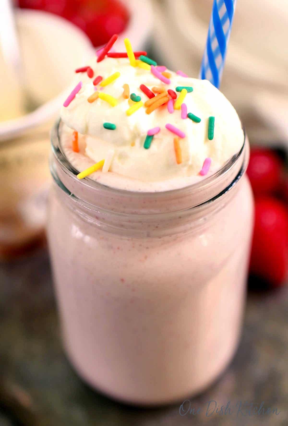 strawberry milkshake in a mason jar with whipped cream.