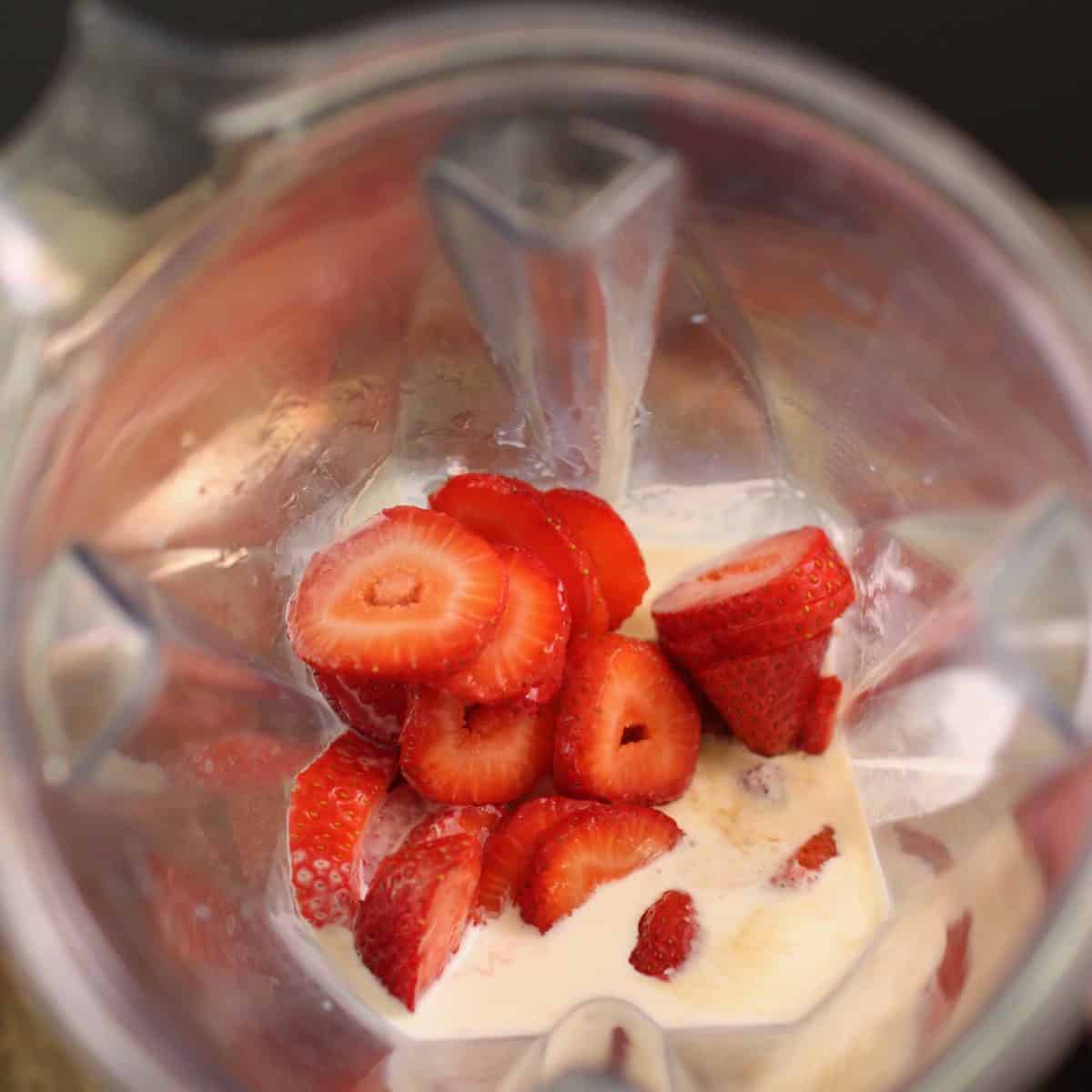a strawberry milkshake in a mason jar on a tray next to a carton of ice cream.