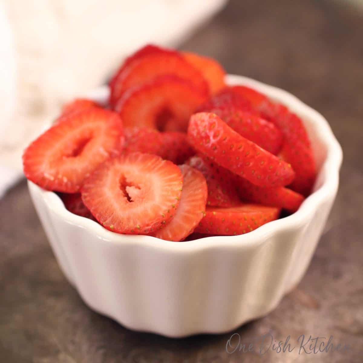 a white bowl filled with sliced strawberries.