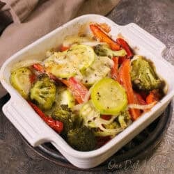 a single serving vegetable casserole with fresh vegetables, cheese and herbs in a small baking dish.