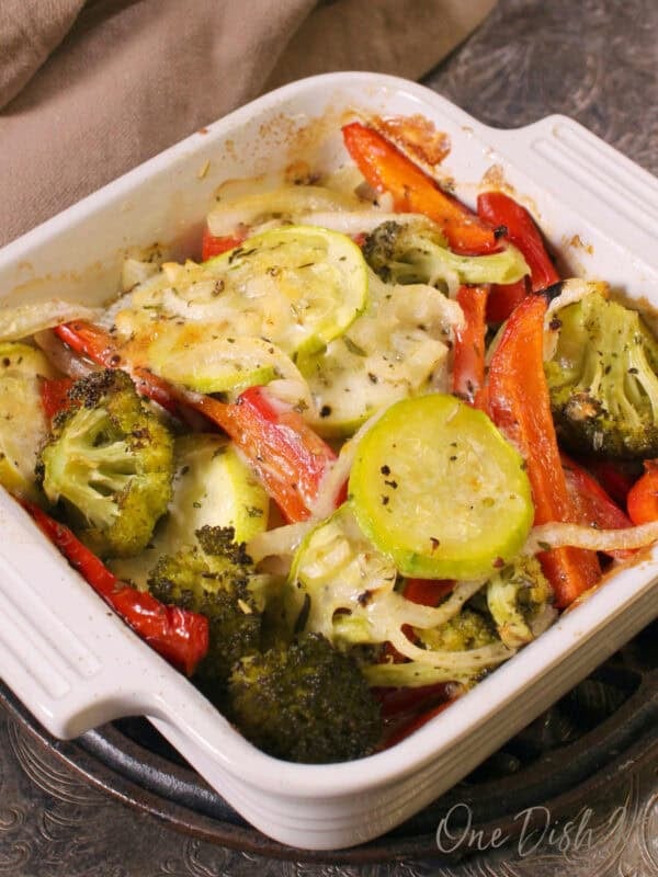 a single serving vegetable casserole with fresh vegetables, cheese and herbs in a small baking dish.