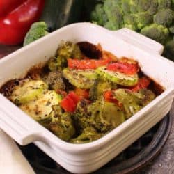 a vegetable casserole next to fresh peppers and broccoli.