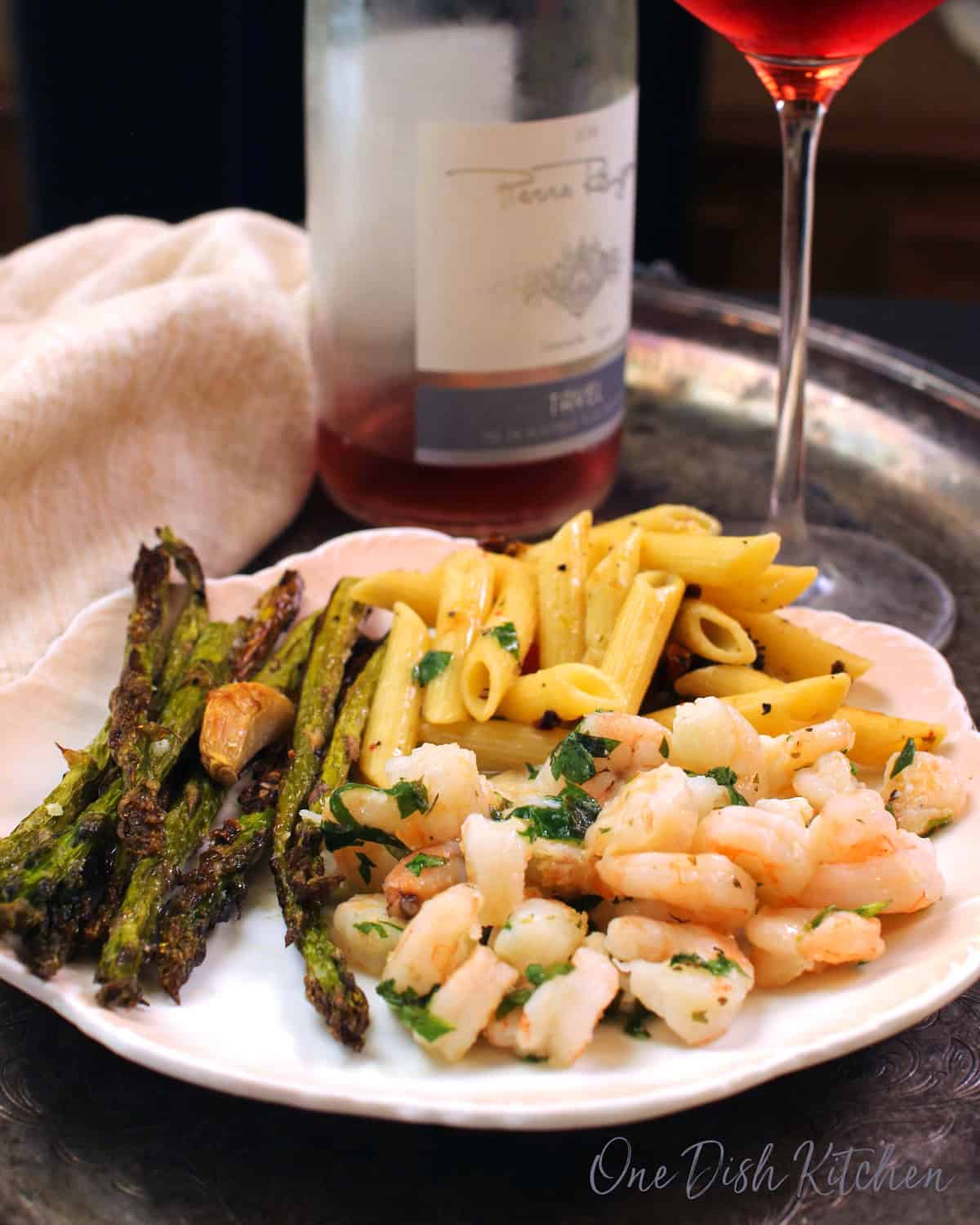 baked shrimp with pasta and asparagus on a white plate.