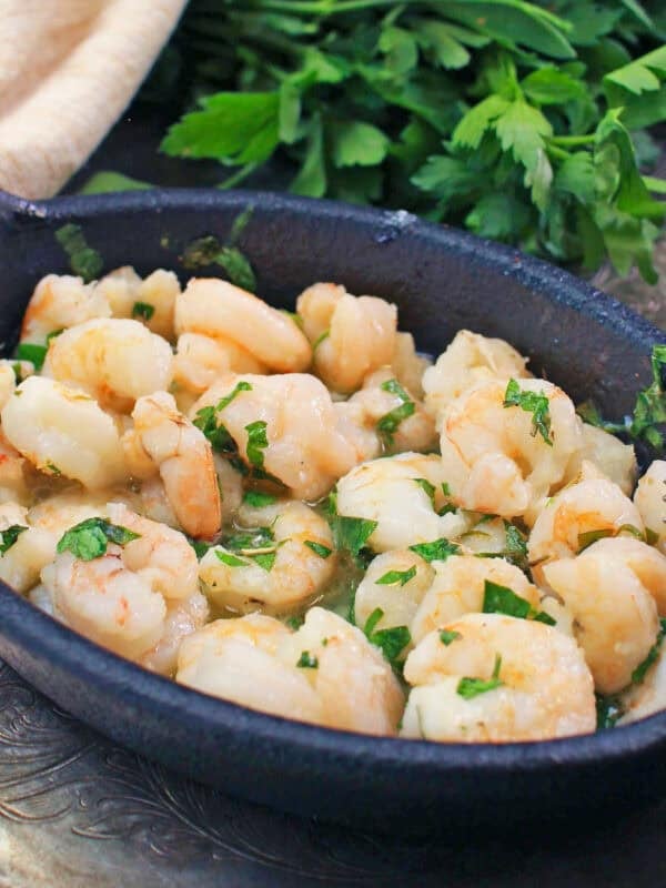 a bowl of baked shrimp on a silver tray.