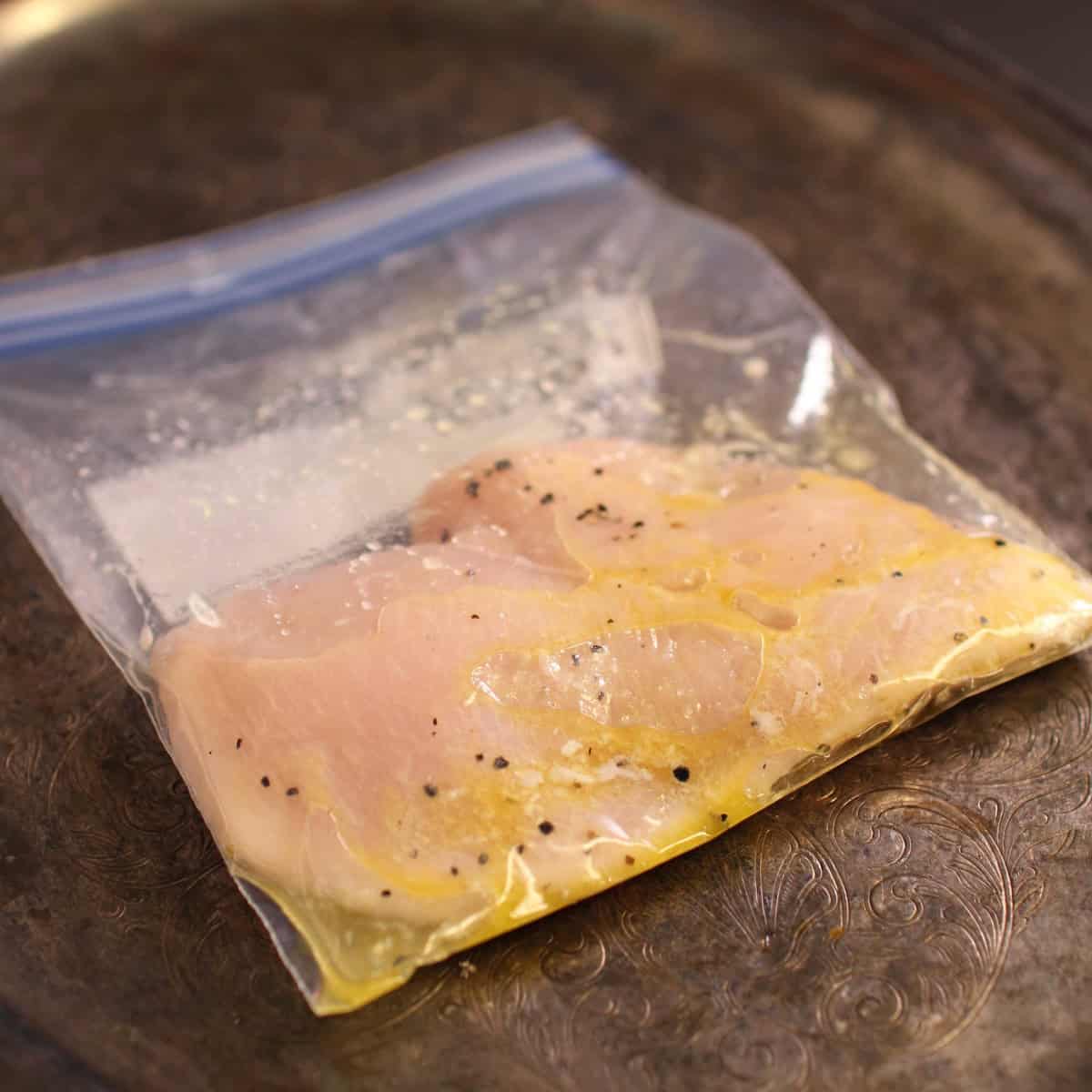 a chicken breast marinating in a zip top bag.