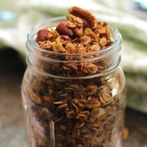 a mason jar filled with a small batch of butter pecan granola next to a green napkin