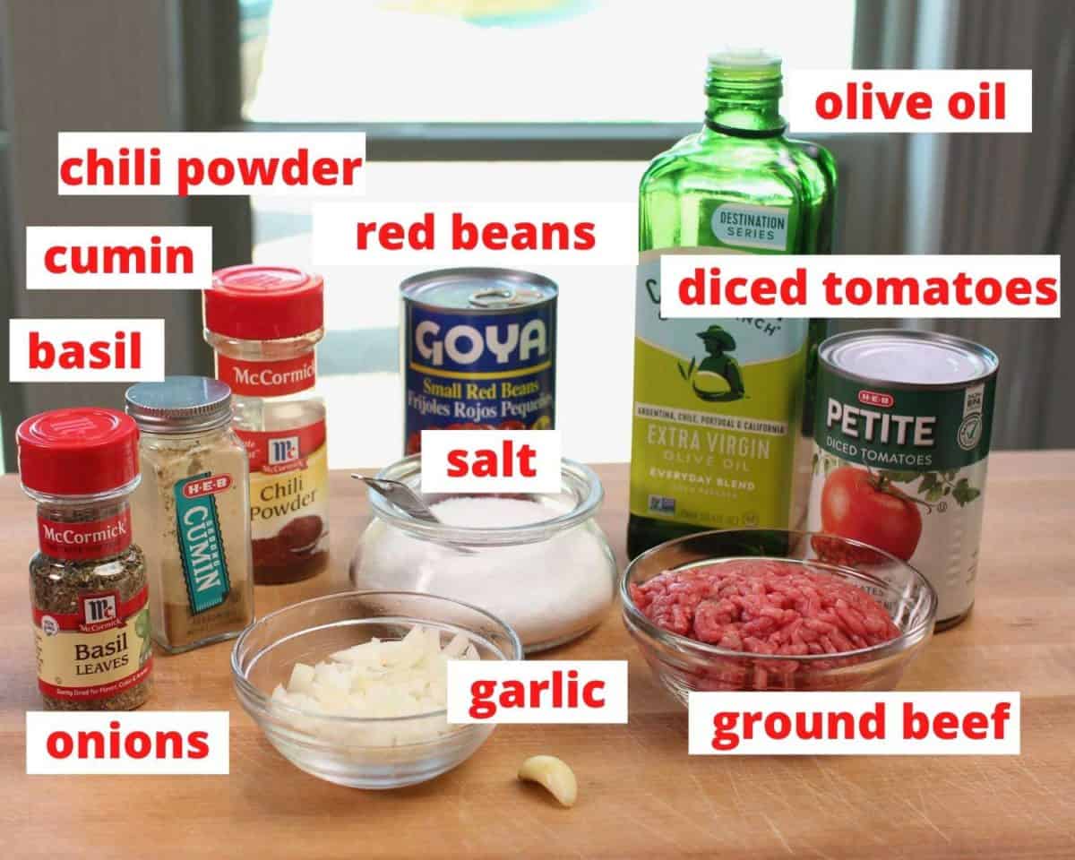 ingredients to make chili on a wooden cutting board labeled.