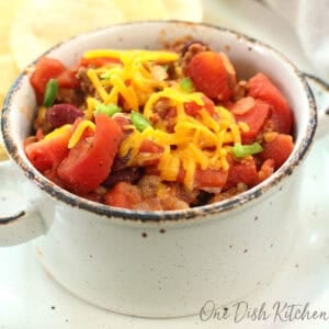 a small bowl of homemade chili with ground beef, tomatoes, and cheese.