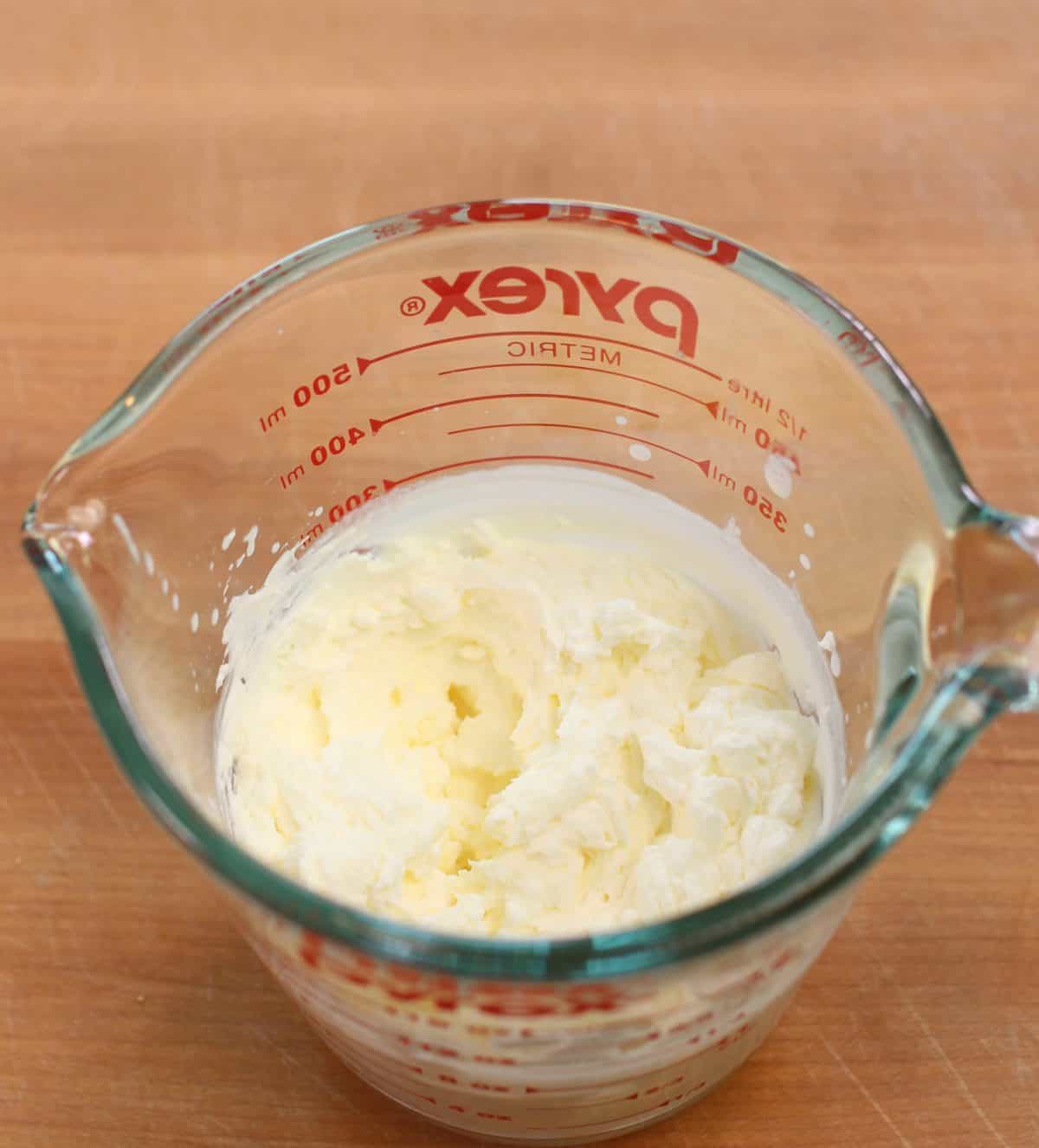 a measuring cup filled with homemade whipped cream.