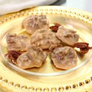 a gold rimmed plate filled with six pecan pralines
