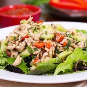 a poached chicken breast on lettuce with vegetables.