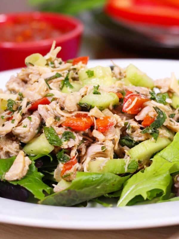 a poached chicken breast on lettuce with vegetables.