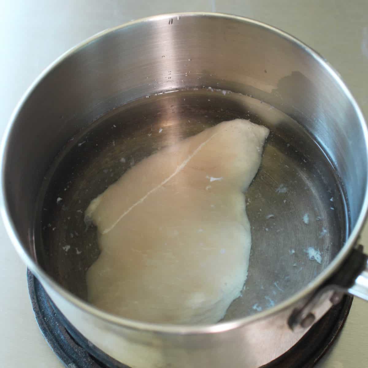 a piece of chicken in a pot of water.