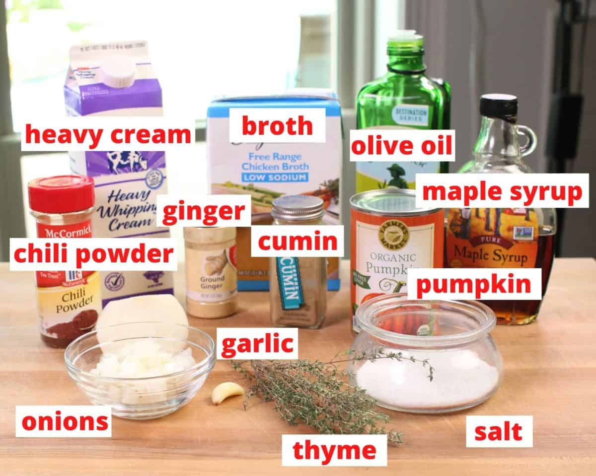 The ingredients used in a pumpkin soup recipe labeled on a brown table.