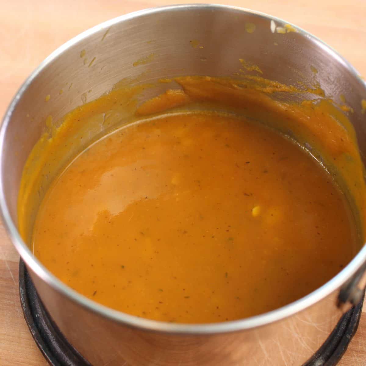a pot of pumpkin soup on a brown table.