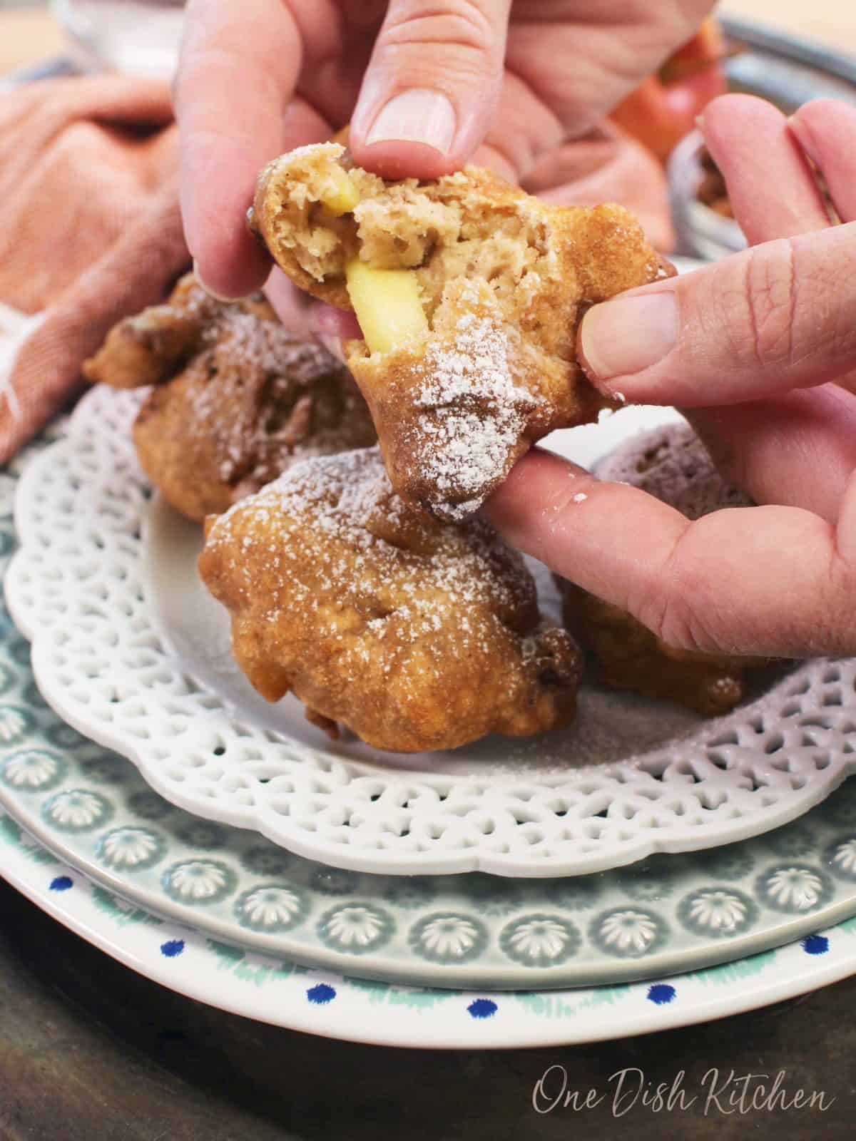 two hands pulling apart an apple fritter.