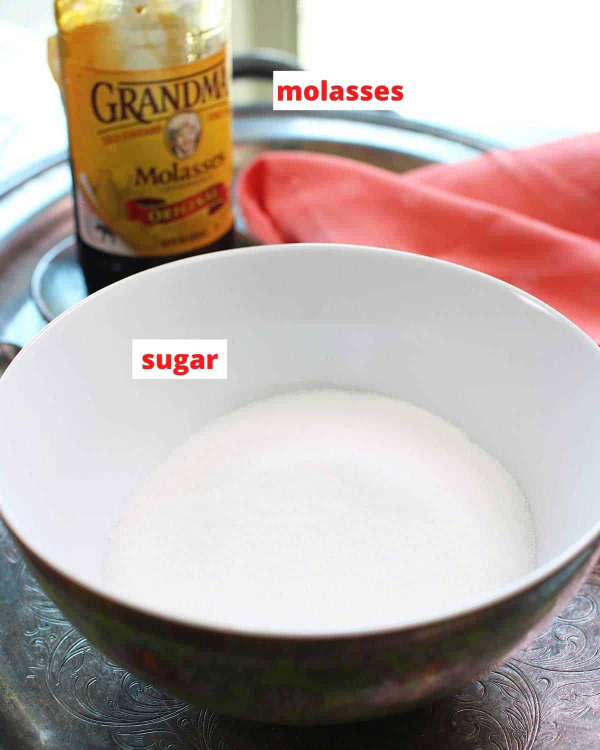 a bowl of sugar and a jar of molasses on a silver tray.