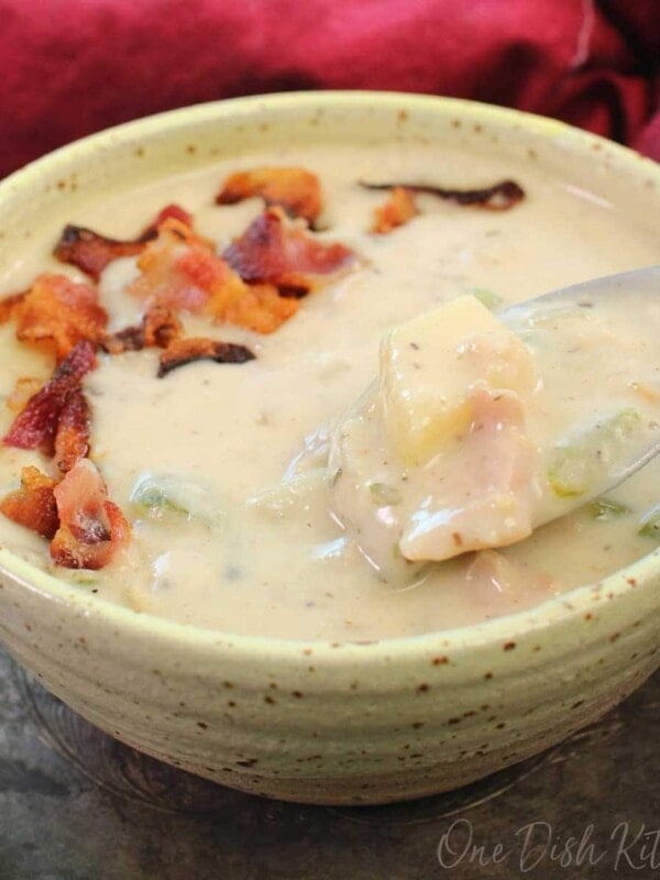 a yellow bowl filled with clam chowder topped with crumbled bacon