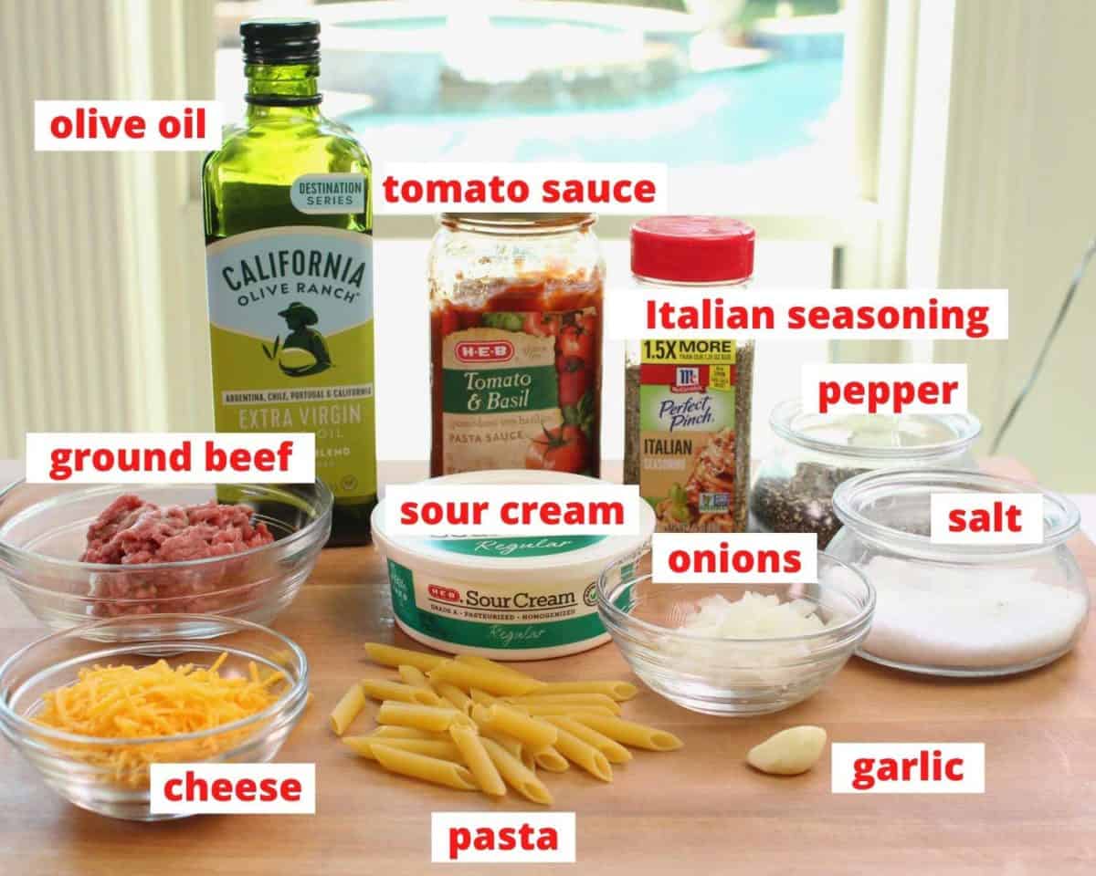 the ingredients needed to make a hamburger casserole on a brown cutting board.