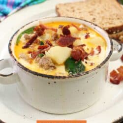 a bowl of zuppa toscana next to a few slices of bread.