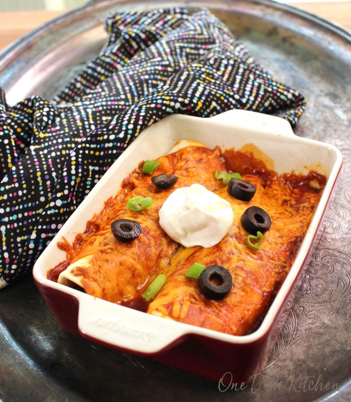 two beef enchiladas in a red baking dish.