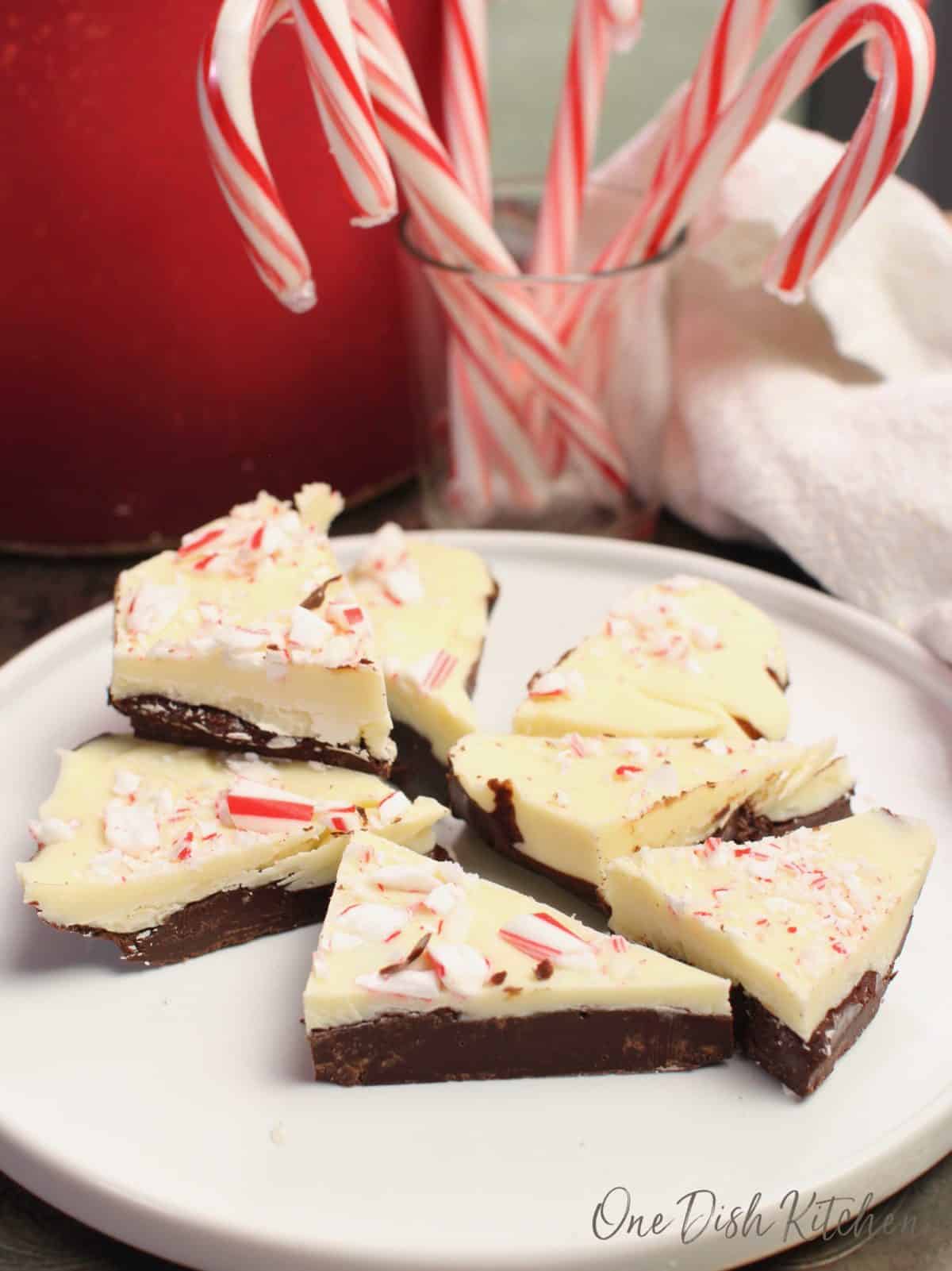 a white plate filled with pieces of peppermint bark next to a white napkin.