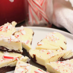 a plate of peppermint bark next to a red vase.