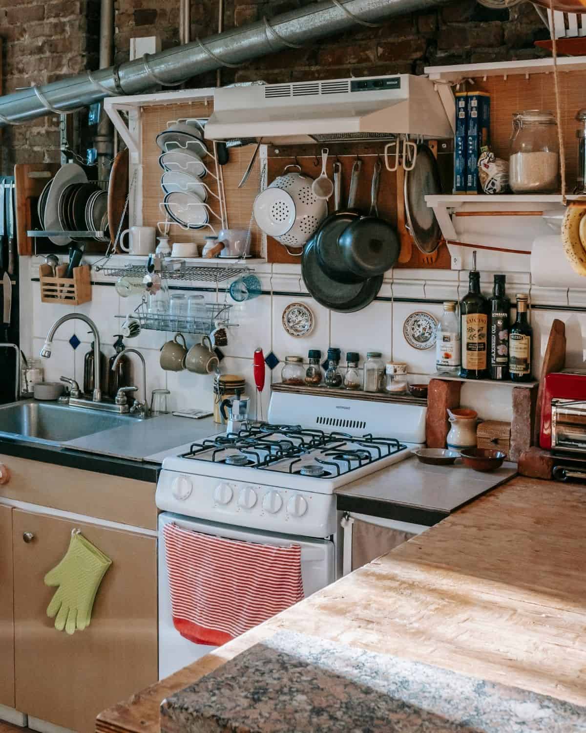 a small kitchen with a white stove and pans hanging from the ceiling