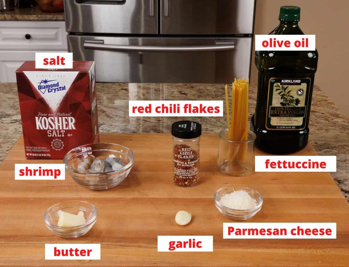 ingredients in shrimp fettuccine on a wooden cutting board.