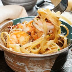 shrimp and fettuccine on a fork over a big bowl of pasta