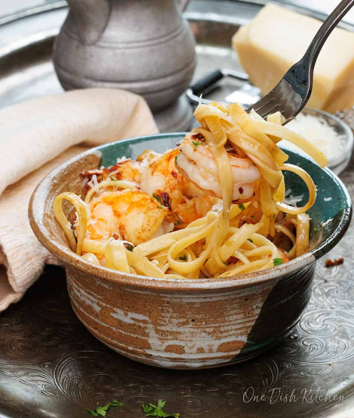 shrimp and fettuccine on a fork over a big bowl of pasta.