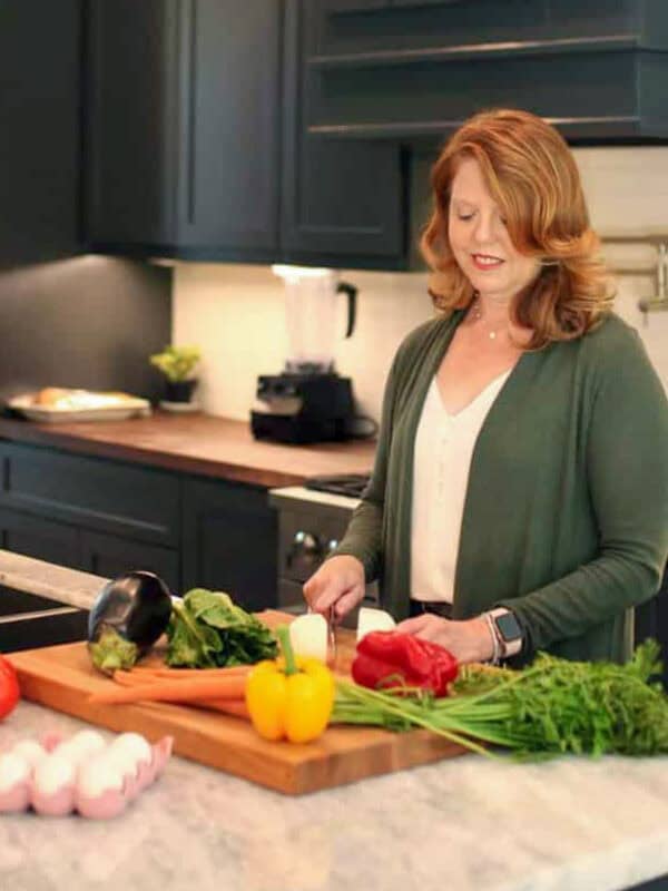 a woman in a kitchen slicing vegetables.