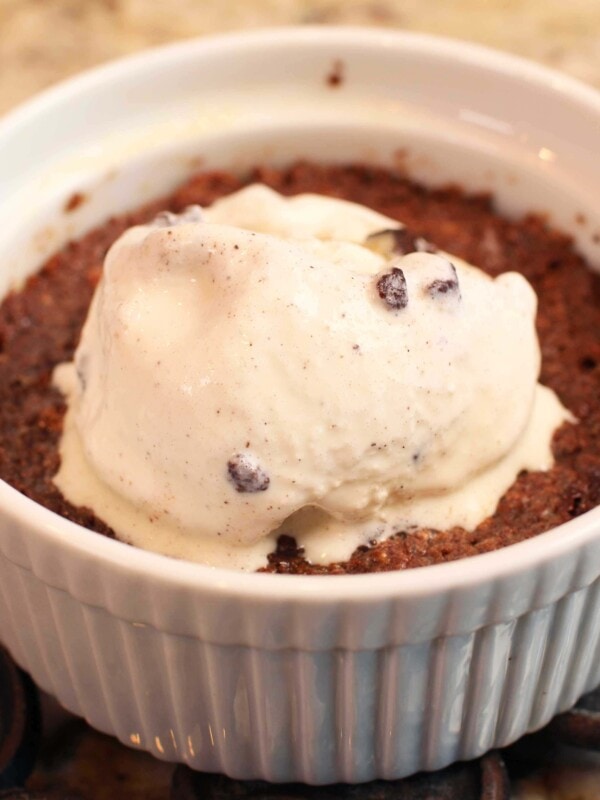a brownie in a white round dish with ice cream on top