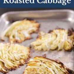 four roasted cabbage wedges on a baking sheet.