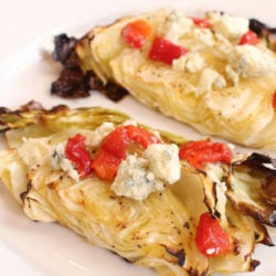 two slices of baked cabbage on a plate topped with cheese.