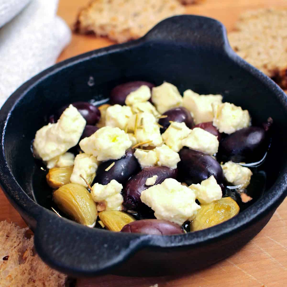 roasted garlic with olives and feta in a small dish.