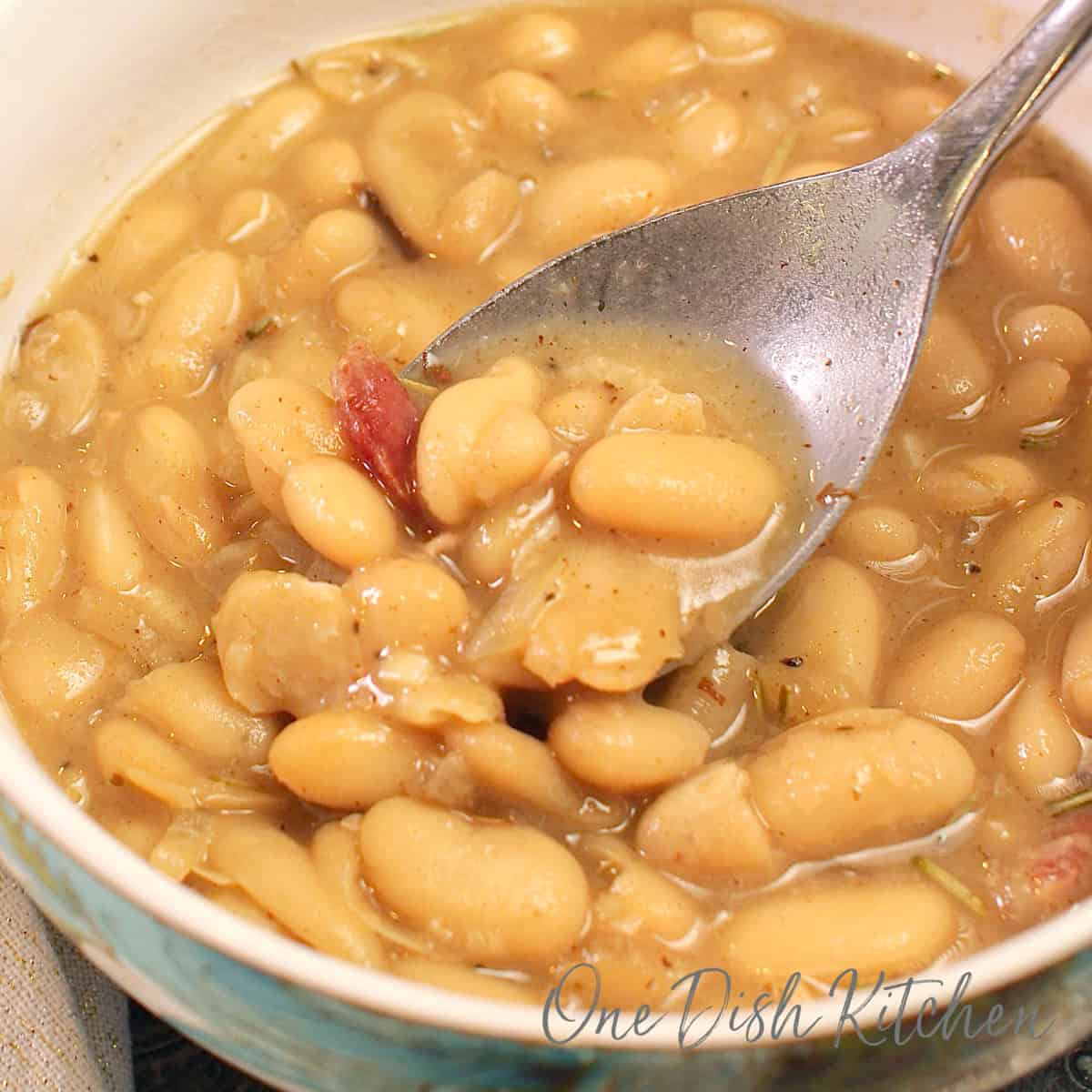 a single serving of creamy white bean soup in a bowl with a spoon on the side.