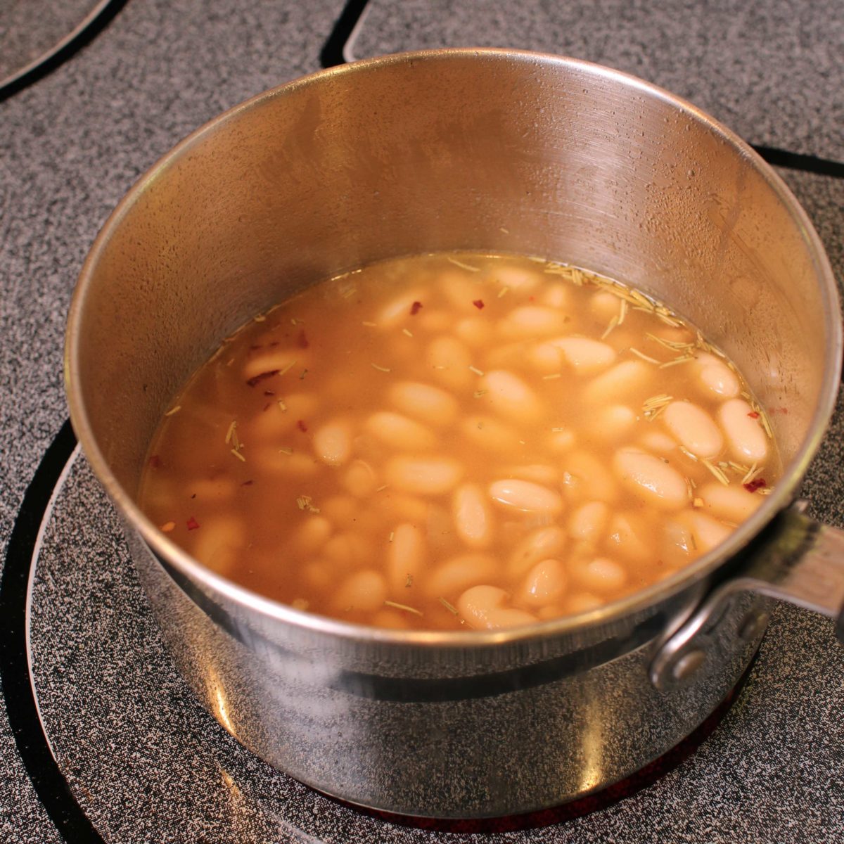 a pot of beans simmering in a broth.