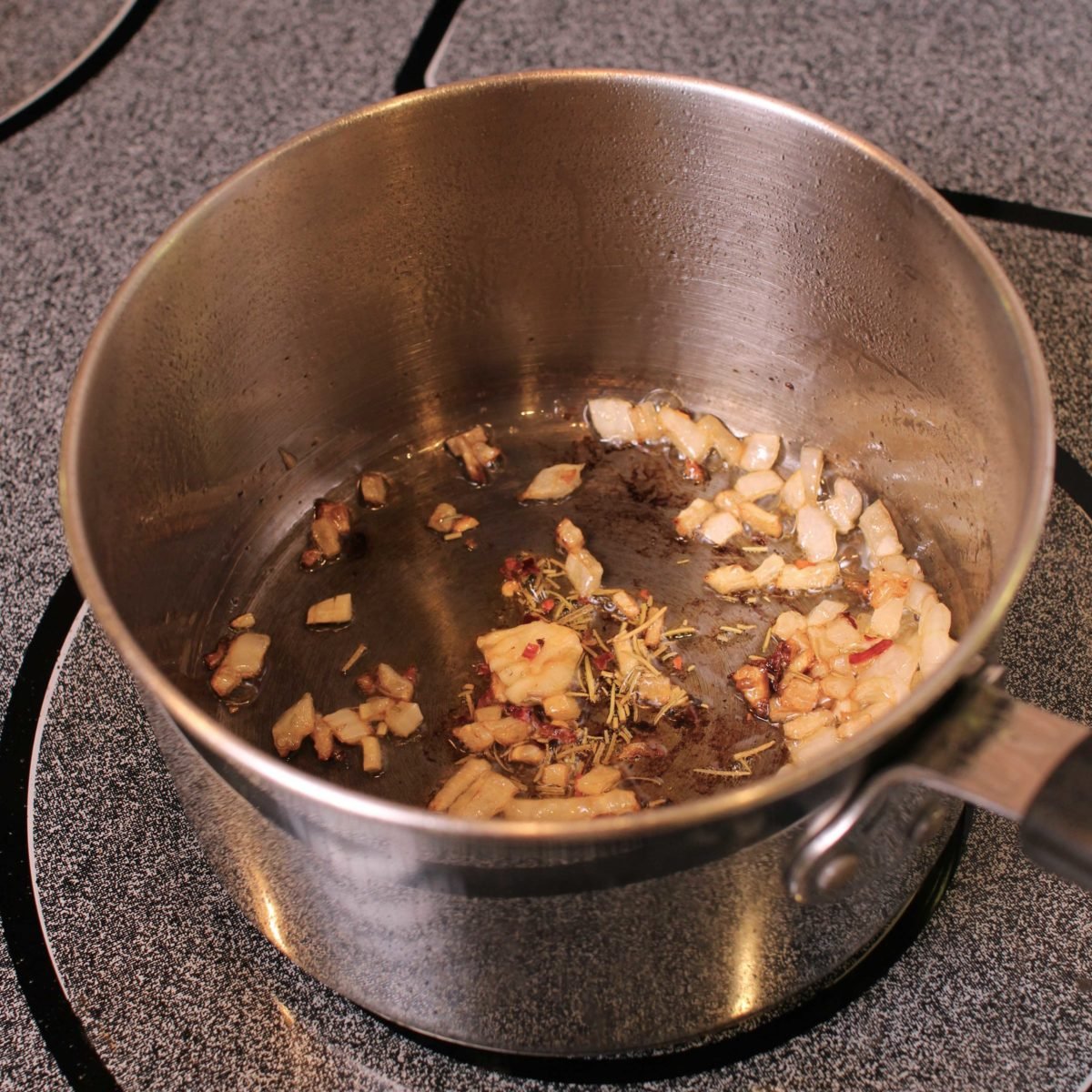 chopped onions and garlic in a silver pot on a stove.