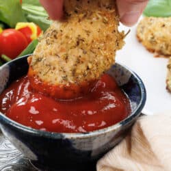 one chicken tender being dipped in a bowl of ketchup