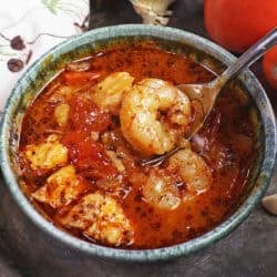 a bowl of cioppino filled with shrimp and white fish.