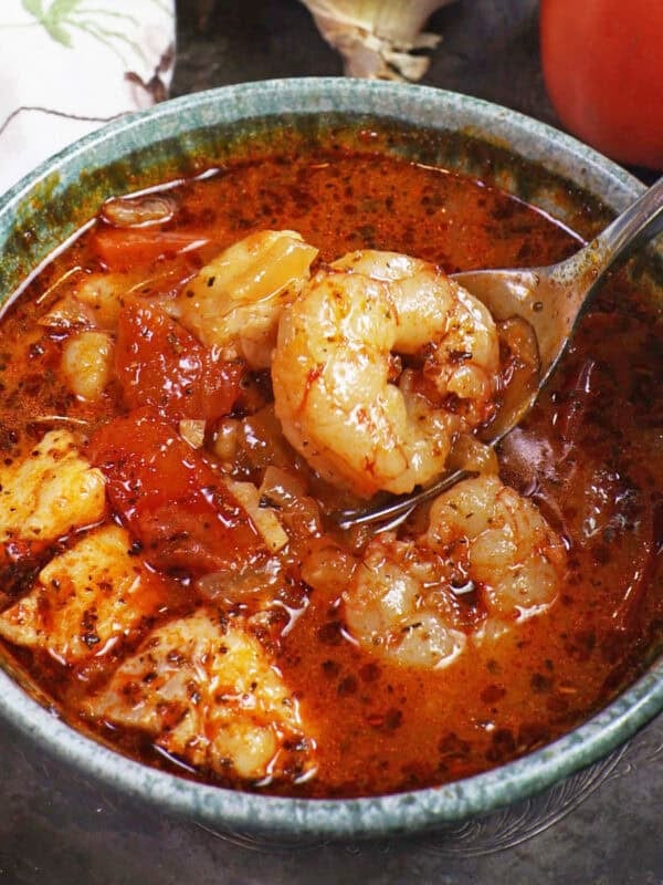 a bowl of cioppino filled with shrimp and white fish.