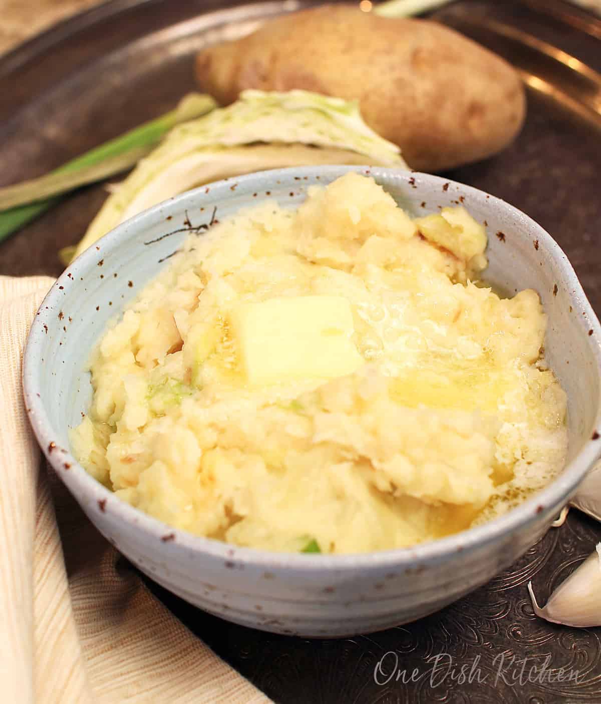 Single serving bowl of Irish colcannon made with creamy mashed potatoes, tender cabbage, butter, and green onions.